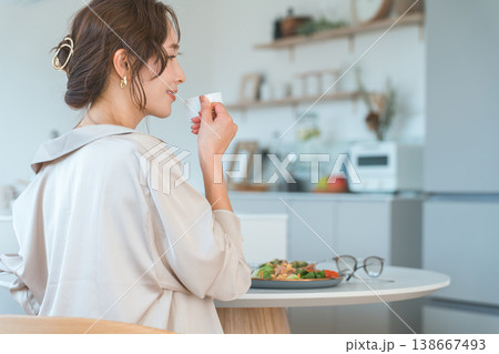 ダイニングテーブルで食事をする笑顔の女性の横顔 138667493