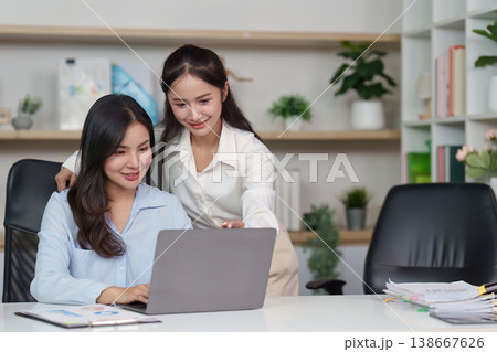 Colleagues collaborating on a laptop in a modern office 138667626