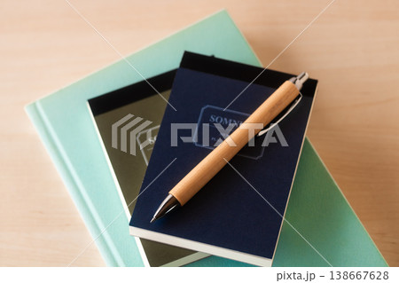 本の上のメモ帳とボールペン 138667628