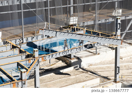 鉄骨建設現場でクレーン吊り上げ中の鉄骨梁を誘導し据え付ける作業員4 138667777