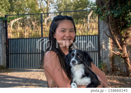Portrait of a smiling young Chinese woman hugging her beloved pet in a picturesque rural setting. Portrait of a smiling young Chinese woman hugging her beloved pet in a picturesque rural setting. 138668145