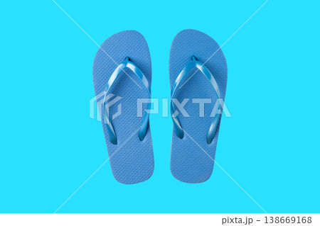 Blue flip flops sit on a bright blue background with style 138669168