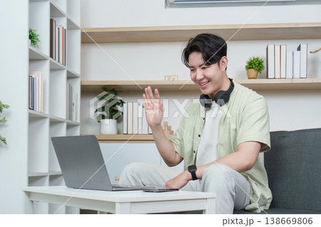 Man waving during video call on laptop at home Man waving during video call on laptop at home 138669806