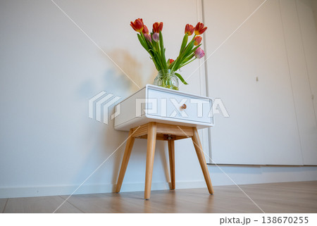 Minimalist interior with tulip bouquet in glass jar on bedside table modern Scandinavian home decor 138670255