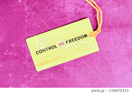 A rectangular yellow tag features the words Control VS Freedom in black and pink letters. It rests on a textured magenta background A rectangular yellow tag features the words Control VS Freedom in black and pink letters. It rests on a textured magenta background 138670353