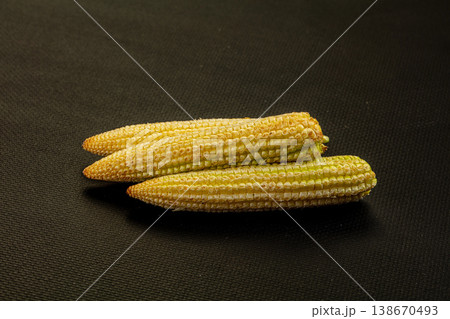 Pile of fresh raw baby corn on a textured background 138670493