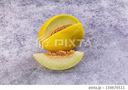 Fresh ripe yellow melon with a slice and visible seeds on a rustic background. Fresh ripe yellow melon with a slice and visible seeds on a rustic background. 138670511
