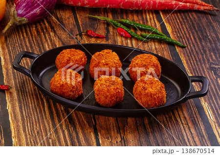 Golden fried cheese and vegetable balls, appetizer dish with fresh chili, peppers, and carrots on a wood table. Golden fried cheese and vegetable balls, appetizer dish with fresh chili, peppers, and carrots on a wood table. 138670514
