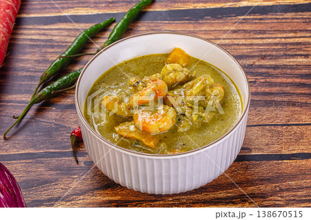 Thai green curry with shrimp and broccoli in a bowl, surrounded by fresh ingredients on a wooden table Thai green curry with shrimp and broccoli in a bowl, surrounded by fresh ingredients on a wooden table 138670515