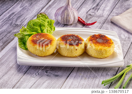 Pan-fried savory cakes with lettuce garnish, garlic, and chili on a rustic table Pan-fried savory cakes with lettuce garnish, garlic, and chili on a rustic table 138670517