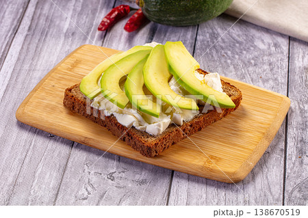 Avocado toast with cream cheese on a rustic wooden cutting board Avocado toast with cream cheese on a rustic wooden cutting board 138670519