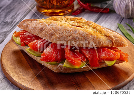 Smoked salmon and avocado sandwich with cream cheese on ciabatta bread, served on a rustic wooden board. 138670525