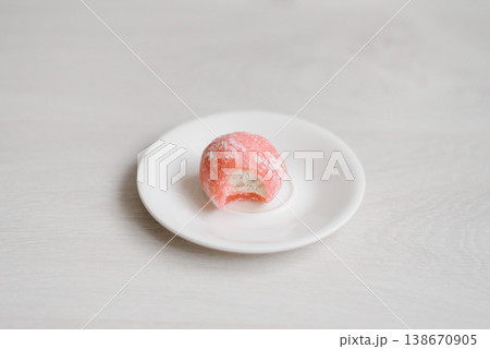 Bitten Pink Mochi Cake Showing White Cream Filling on Small White Saucer 138670905