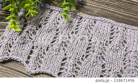 A raised openwork pattern knitted with colored yarn on a wooden background. A raised openwork pattern knitted with colored yarn on a wooden background. 138671456