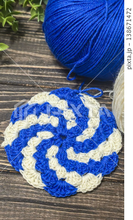 A raised openwork pattern knitted with colored yarn on a wooden background. A raised openwork pattern knitted with colored yarn on a wooden background. 138671472