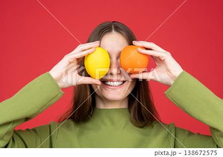 Cheerful woman hiding eyes with citrus fruits 138672575