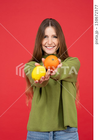 Cheerful woman holding out citrus fruits Cheerful woman holding out citrus fruits 138672577