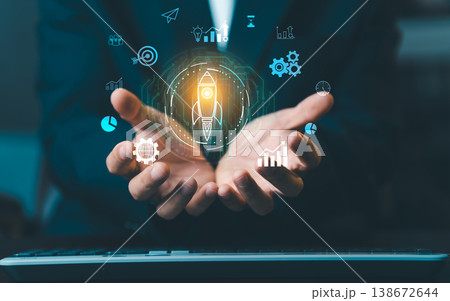 Businessman hands holding glowing rocket icon with business startup and growth symbols. Concept of project launch, innovation, and career success. Businessman hands holding glowing rocket icon with business startup and growth symbols. Concept of project launch, innovation, and career success. 138672644