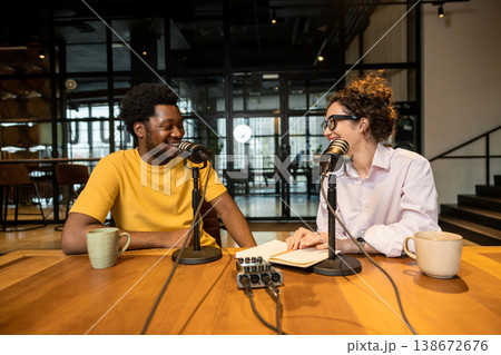 Colleagues smiling and talking in microphones during interview Colleagues smiling and talking in microphones during interview 138672676