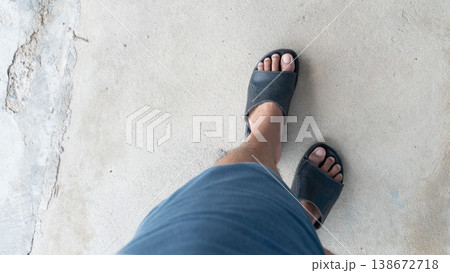 Above view of man wearing shorts and black leather sandals is walking on the ground. Standing on old cement floor. Above view of man wearing shorts and black leather sandals is walking on the ground. Standing on old cement floor. 138672718