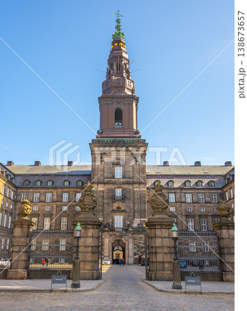 Christiansborg Palace, located on Slotsholmen, showcases stunning architecture under a clear blue sky. Visitors admire its historic significance and grandeur during their exploration. 138673657