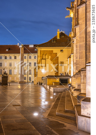The Mrakotin Monolith stands tall at Prague Castle, surrounded by historical buildings, as warm light casts dramatic shadows on the cobblestone ground under the night sky. The Mrakotin Monolith stands tall at Prague Castle, surrounded by historical buildings, as warm light casts dramatic shadows on the cobblestone ground under the night sky. 138673685