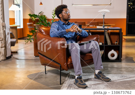 Man sitting in leather chair holding pencil Man sitting in leather chair holding pencil 138673762