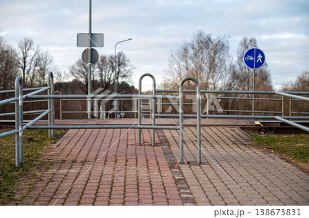 Pedestrian crossing on railway tracks with railings and signs near the path 138673831