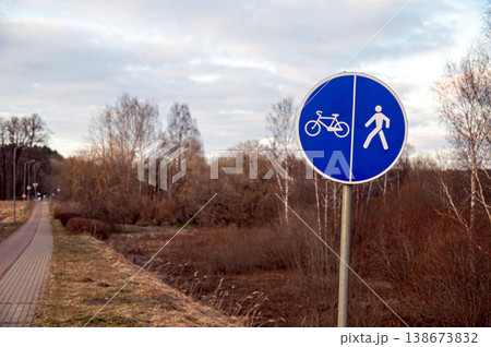 Bike and pedestrian lane sign on pathway near trees in early evening Bike and pedestrian lane sign on pathway near trees in early evening 138673832