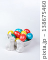 White Porcelain Bunnies and Painted Easter Eggs in Ceramic Bowl on White Background 138675460