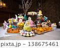 Festive Easter dessert table with colorful cakes, eggs, and floral decorations on stone wall 138675461