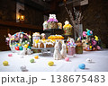 Festive Easter dessert table with colorful cakes, eggs, and floral decorations on stone wall 138675483