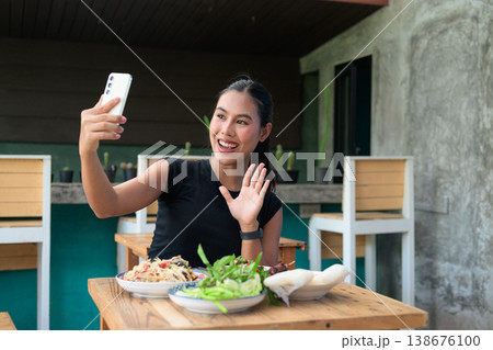 Happy Thai Woman Video Calling with Smartphone at Restaurant Table with Isan Food Papaya Salad Happy Thai Woman Video Calling with Smartphone at Restaurant Table with Isan Food Papaya Salad 138676100