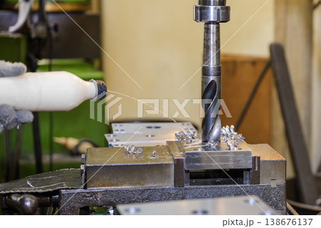 Heavy-duty hole making process on an NC milling machine using a large drill bit with manual coolant application. 138676137