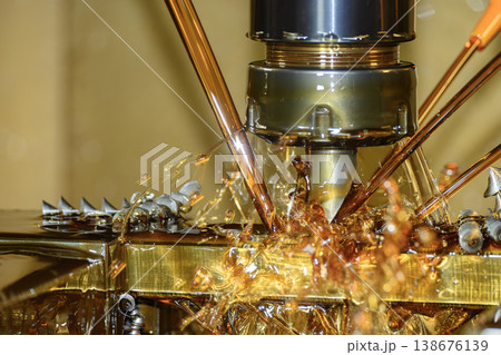 Macro shot of a high-pressure oil coolant stream during a CNC milling roughing process with indexable tooling. Macro shot of a high-pressure oil coolant stream during a CNC milling roughing process with indexable tooling. 138676139