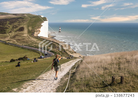 Hiker walking on a path towards the white cliffs and ocean Hiker walking on a path towards the white cliffs and ocean 138677243