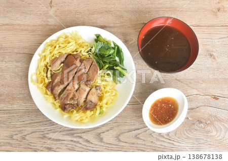 Chinese yellow egg nodles topping braised slice pork leg stew dressing black herb soup couple pickled cabbage and kale dipping spicy sour chili sauce on plate Chinese yellow egg nodles topping braised slice pork leg stew dressing black herb soup couple pickled cabbage and kale dipping spicy sour chili sauce on plate 138678138