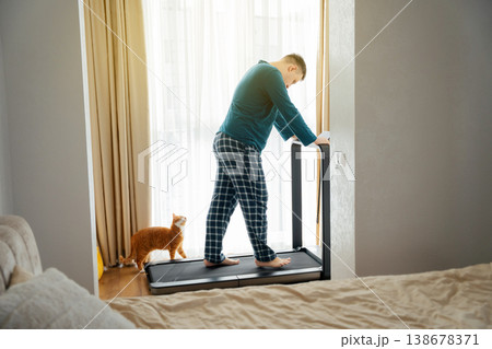 A 35 year old Caucasian man with his ginger cat walks on a treadmil 138678371