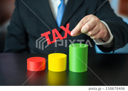 A businessman holds a sign Tax over a growth chart. Concept of increasing taxes on business A businessman holds a sign Tax over a growth chart. Concept of increasing taxes on business 138678406