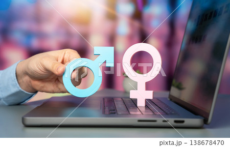 Man holds male and female gender symbols on a laptop keyboard. 138678470