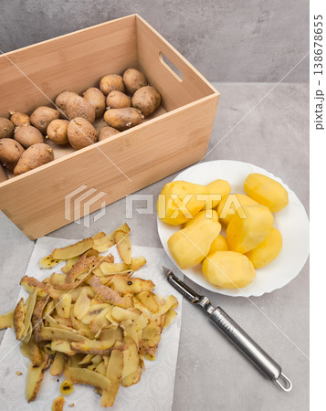 Peeled potatoes, peels, peeler, and unpeeled potatoes in a wooden box on a kitchen counter Peeled potatoes, peels, peeler, and unpeeled potatoes in a wooden box on a kitchen counter 138678655