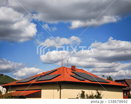 Solar panels on a modern rooftop under a dramatic sky filled with clouds showcasing renewable energy solutions and sustainable living concept Solar panels on a modern rooftop under a dramatic sky filled with clouds showcasing renewable energy solutions and sustainable living concept 138678692