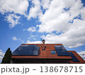 Solar panels installed on a modern rooftop under a bright blue sky with fluffy clouds showcasing renewable energy and sustainability concept 138678715