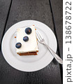 Delicious cake topped with cream and fresh blueberries on a white plate dessert concept. copy space 138678722