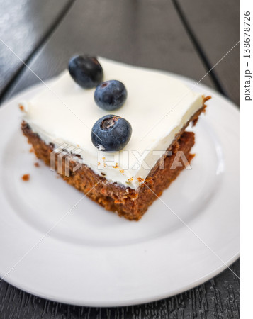 Delicious carrot dessert slice topped with cream and fresh blueberries showcasing a sweet treat concept. copy space Delicious carrot dessert slice topped with cream and fresh blueberries showcasing a sweet treat concept. copy space 138678726