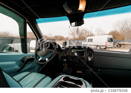 Interior view of a modern commercial van dashboard and steering wheel in light blue and black tones. 138679206