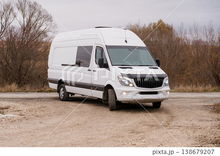 White commercial delivery van parked on a dirt road with trees and dry grass in a natural setting. 138679207