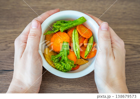 Hands holding bowl with vegetable chips made from broccoli carrot and sweet potato. Healthy snack and clean eating lifestyle concept. 138679573