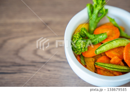 Mixed vegetable chips in bowl with copy space on wooden background. Healthy snack and clean eating concept without salt sugar or additives. Soft focus photo 138679585