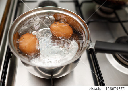 Saucepan stainless steel with boiling eggs breakfast in water on gas stove. 138679775